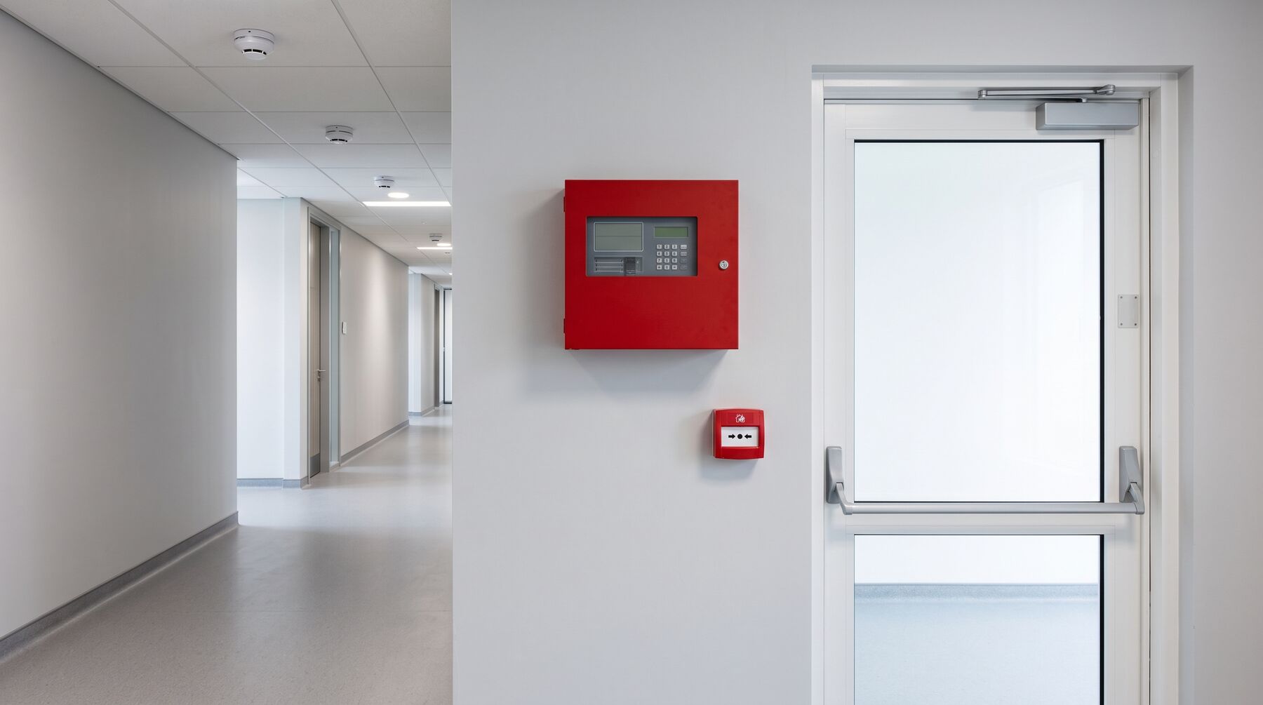 Fire alarm panel and call point beside a fire exit door
